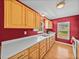 Well-lit kitchen featuring light wood cabinets, ample counter space, stainless steel appliances, and a red accent wall at 10925 Fort King Rd, Dade City, FL 33525