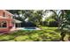 Lush backyard with mature plants bordering the pool and home at 1550 Chateau Wood Dr, Clearwater, FL 33764