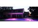 Stunning backyard featuring an illuminated pool, covered patio, and a barbecue, ideal for relaxation and outdoor entertaining at 1550 Chateau Wood Dr, Clearwater, FL 33764