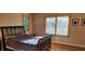 Sunlit bedroom with a dark wooden bed frame, hardwood floors, and natural light from two large windows at 1550 Chateau Wood Dr, Clearwater, FL 33764