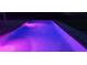 Beautifully lit pool at night with cool blue and pink hues creating an enchanting and inviting atmosphere at 1550 Chateau Wood Dr, Clearwater, FL 33764