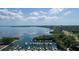 Aerial view of a marina with boats docked along the water's edge, surrounded by trees and a picturesque shoreline at 1857 Castle Woods Dr, Clearwater, FL 33759