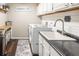Bright laundry room with white cabinets, washer, dryer, sink, and wood-look floors at 1857 Castle Woods Dr, Clearwater, FL 33759