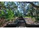 Stone steps lead to a scenic pathway under mature trees, offering an inviting entrance to the park at 1857 Castle Woods Dr, Clearwater, FL 33759
