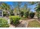 Backyard featuring a brick pathway and diverse trees and landscaping surrounding the screened pool and back of home at 2823 Clubhouse Dr, Plant City, FL 33566