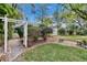 The backyard shows a decorative white arbor, brick pathway, and manicured landscaping for idyllic outdoor living at 2823 Clubhouse Dr, Plant City, FL 33566