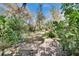A serene backyard features a brick path, lush greenery, mature trees, and a stone bench, creating a peaceful outdoor retreat at 2823 Clubhouse Dr, Plant City, FL 33566