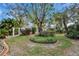 A backyard showcasing a round flower bed and a manicured lawn surrounded by lush landscaping and mature trees at 2823 Clubhouse Dr, Plant City, FL 33566