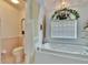 Bright bathroom featuring a soaking tub, toilet, and seashell-themed wallpaper at 2823 Clubhouse Dr, Plant City, FL 33566