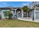 Inviting home entrance with an arched doorway, stone details, manicured lawn, and vibrant tropical landscaping at 2823 Clubhouse Dr, Plant City, FL 33566
