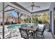 Enclosed pool area with a dining table and seating, surrounded by lush greenery and a jacuzzi at 2823 Clubhouse Dr, Plant City, FL 33566