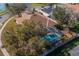 Aerial view of the home showcasing the screened-in pool, mature trees, and roof at 3017 Minuteman Ln, Brandon, FL 33511