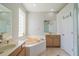 Bright bathroom featuring a soaking tub, double sinks, glass block window and wood cabinets at 3017 Minuteman Ln, Brandon, FL 33511