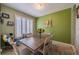 Dining room with a wooden table, six chairs, bright green accent wall, and natural light from shuttered windows at 3017 Minuteman Ln, Brandon, FL 33511