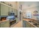 Well-lit eat-in kitchen boasts stainless steel appliances and light green cabinetry at 3017 Minuteman Ln, Brandon, FL 33511