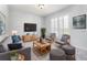 Modern living room with grey sofa, woven chairs, and a wooden media center with a large screen TV at 3017 Minuteman Ln, Brandon, FL 33511