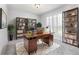 Home office with a large wooden desk, built-in shelving, decorative plants, and natural light from the plantation shutters at 3017 Minuteman Ln, Brandon, FL 33511