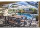 Screened-in patio featuring a large wood table and seating for six overlooks the sparkling blue swimming pool at 3017 Minuteman Ln, Brandon, FL 33511