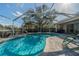 A serene screened-in swimming pool and paver deck area, with chairs and landscaping, is ready for entertaining and fun at 3017 Minuteman Ln, Brandon, FL 33511