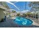 A view of the sparkling blue screened in pool with brick pavers, landscaping, and clear blue skies above at 3017 Minuteman Ln, Brandon, FL 33511