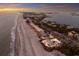 Panoramic aerial view showcases beachfront property, coastal homes, and sunset hues over the ocean at 3341 Gulf Of Mexico Dr, Longboat Key, FL 34228