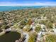 Aerial view of a home surrounded by lush trees with a lake and water in the background at 470 Hibiscus N Ln, Dunedin, FL 34698
