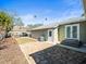 Home backyard features stone patio, white door, lush greenery, and shaded carport at 470 Hibiscus N Ln, Dunedin, FL 34698