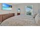 A bright bedroom featuring a large bed, mirrored closet doors, and TV, offering a view to the outdoors at 5456 Logan Cave Ave, Wimauma, FL 33598