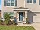 Charming front entrance with a blue door, manicured shrubs, and well-maintained lawn at 5456 Logan Cave Ave, Wimauma, FL 33598