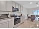 Well-lit kitchen featuring stainless steel appliances and gray cabinets with light granite countertops, perfect for cooking and entertaining at 5456 Logan Cave Ave, Wimauma, FL 33598