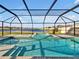 Enjoy this screened-in pool with a relaxing spa, stone tile flooring, and a beautiful lake view at 5456 Logan Cave Ave, Wimauma, FL 33598