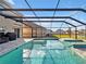 Enjoy this screened-in pool with a relaxing spa, stone tile flooring, and a beautiful lake view at 5456 Logan Cave Ave, Wimauma, FL 33598