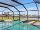Enjoy this screened-in pool with a relaxing spa, stone tile flooring, and a beautiful lake view at 5456 Logan Cave Ave, Wimauma, FL 33598