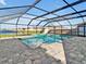 Enjoy this screened-in pool with a relaxing spa, stone tile flooring, and a beautiful lake view at 5456 Logan Cave Ave, Wimauma, FL 33598