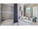 Well-lit bathroom with gray tiled walls, a shower-tub combo and modern vanity at 757 Steel Dr, Apollo Beach, FL 33572