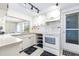 Bright kitchen featuring white cabinets, tile countertops, and a window above the sink at 8601 Lincolnshire Dr, Hudson, FL 34667