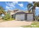 Charming home featuring a paver driveway, tile roof, stone accents, and a manicured lawn with palm trees at 11930 Perennial Pl, Bradenton, FL 34211