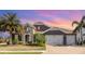 Stunning home featuring a stone facade, paver driveway, tropical landscaping, and a three-car garage at 11930 Perennial Pl, Bradenton, FL 34211