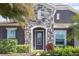 Close-up of a stone facade and front door with leaded glass sidelights surrounded by lush landscaping at 11930 Perennial Pl, Bradenton, FL 34211