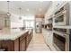 Gourmet kitchen featuring stainless steel appliances, granite countertops, white cabinets, and a farmhouse sink at 11930 Perennial Pl, Bradenton, FL 34211