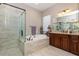 This bathroom features a glass shower, a garden tub, a double sink, and warm beige decor at 11930 Perennial Pl, Bradenton, FL 34211