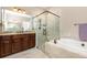 This bathroom features a glass shower, a garden tub, a double sink, and warm beige decor at 11930 Perennial Pl, Bradenton, FL 34211