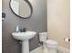 Stylish powder room featuring gray subway tiles, a pedestal sink, modern fixtures, and a round decorative mirror at 11930 Perennial Pl, Bradenton, FL 34211