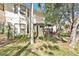 Home's rear exterior featuring mature trees, lush flowerbeds, and a screened-in porch at 15 Emerald Bay Dr, Oldsmar, FL 34677