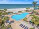 A refreshing pool surrounded by palm trees, with a view of the beach in the background at 1560 Gulf Blvd # 1202, Clearwater Beach, FL 33767
