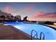 Beautiful in-ground pool at dusk, surrounded by palm trees with condominium buildings in the background at 1560 Gulf Blvd # 1202, Clearwater Beach, FL 33767