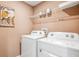 Cozy laundry room with modern washer and dryer, shelving for storage, and a stylish flower print wall decor at 1820 Cobb Trl, Parrish, FL 34219