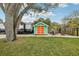 Backyard shed provides storage space with a unique design and is surrounded by a firepit area and mature trees at 1868 Douglas Ave, Dunedin, FL 34698