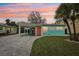 Charming exterior view of a one-story home showcasing colorful accents, a paved driveway, and mature landscaping at 1868 Douglas Ave, Dunedin, FL 34698