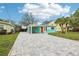 Charming turquoise home with bright orange door, covered parking, and a newly paved driveway at 1868 Douglas Ave, Dunedin, FL 34698